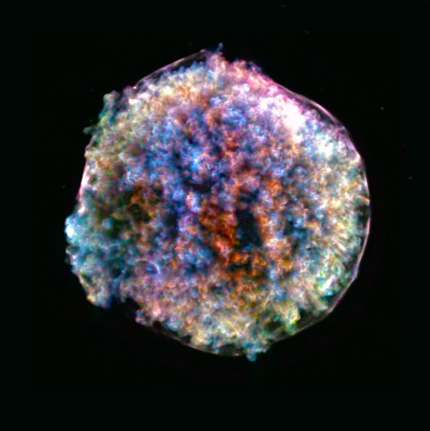 A round, lumpy cloud of glowing gas in shades of blue, purple and pink against a black background, its surface covered in knots and bubbles